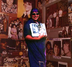 Sister Petunia, happy as ever, surrounded by youthful images of His Supreme Purpleness prior to the age of twenty...